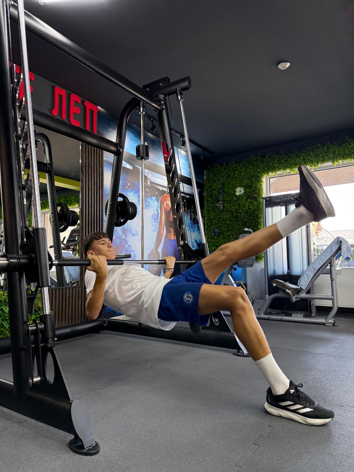 Sportista radi horizontalno veslanje na šipki uz podignutu nogu