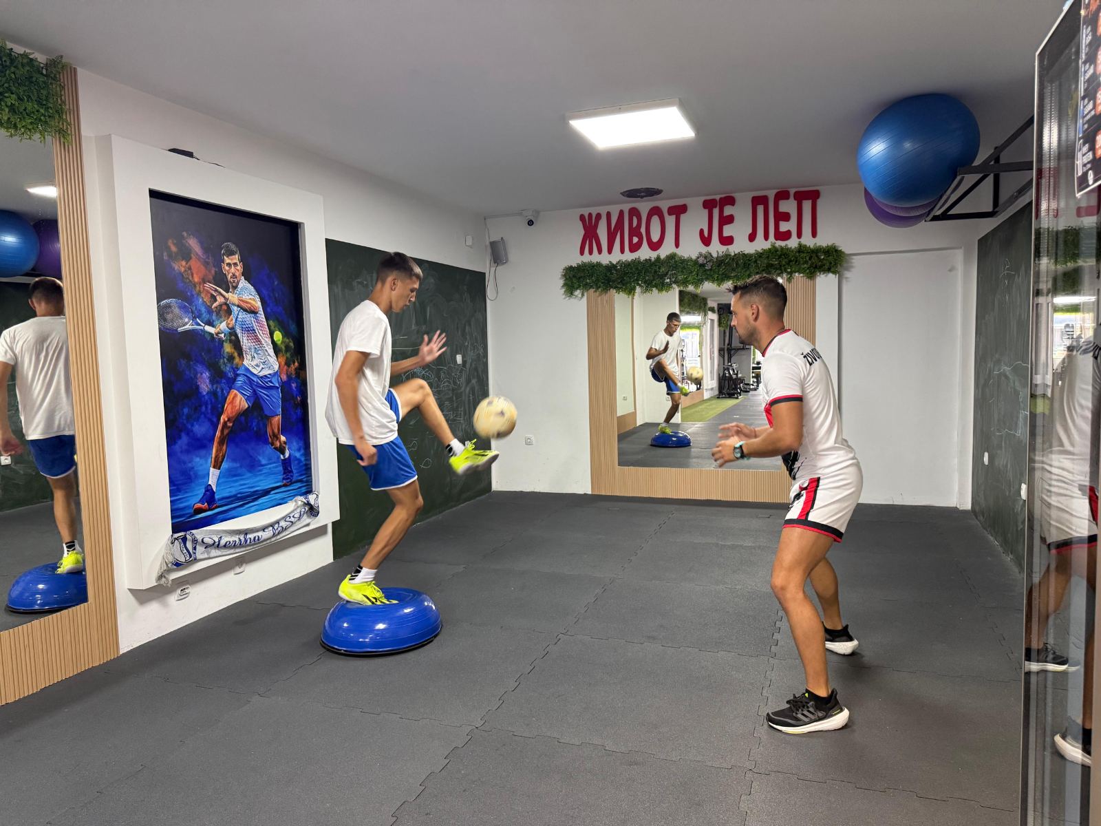 Sportista trenira ravnotežu na bosu lopti sa fudbalskom loptom
